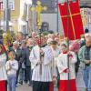 (cpg)   Den Einzug Jesu in Jerusalem und den Auftakt zur Karwoche feierten die Katholiken am Palmsonntag. Im Rathausinnenhof fand die traditionelle Palmweihe der Pfarrei Heilig-Geist statt. Pfarrer Reiner Fries erinnerte an die Besonderheit des Palmsonntags als verhalten festlicher Auftakt zur Karwoche, die gleichzeitig Höhepunkt der Passionszeit ist. Er nahm den mit Kirchenfahnen geschmückten Turm der St. Johanniskirche zum Anlass, um die Konfirmationsfeiern am Palmsonntag bei den evangelischen Christen einzubeziehen. Fries machte deutlich, dass Jesus bewusst nicht auf dem Pferd Einzug gehalten habe, um nicht den Sieger hervorzukehren. Auf dem Esel sei er in Jerusalem eingezogen, um seine Vorstellung vom Reich Gottes sichtbar zu machen, wo einer des andern Last tragen soll. Die Hosianna-Rufe der Hebräer hätten die Hoffnungen des Volkes auf einen Nachfolger König Davids ausgedrückt. Jesus habe stattdessen zum Ausdruck gebracht, den Menschen dienen zu wollen. Daran sei er letztlich gescheitert. Im Anschluss formierte sich ein stattlicher Zug durch die Spitalstraße zurück zur Heilig-Geist-Kirche.