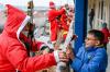Ein Feuerwehr-Nikolaus beschenkt den kleinen Diego (12 Jahre alt) mit Süßigkeiten.