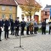 Hauptmann Sebastian Moser, Gemeinderätin Ilona Dusel, Gemeinderäte Eric Dittmann und Michael Ortner erinnern an die Opfer von Krieg und Gewalt in der Vergangenheit und Gegenwart. Mit im Bild: die Abordnung der Patenkompanie der Gemeinde Kolitzheim und Fahnenabordnungen örtlicher Vereine. Im Hintergrund die Musikkapelle Spiesheim.