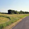 Von rechts, aus Richtung des Baches Weisach kommend, wird der Bach und dann diese Straße (hier Blick Richtung Kraisdorf) unterbohrt und das Stromkabel um die Umzäunung des Brunnens 2 (oben links) verlegt