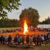 Die Teilnehmer am Zeltlager der Pfarreiengemeinschaft versammelt um ein Lagerfeuer.