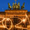 Die Zahl 2021 ist mit einer Wunderkerze während einer Langzeitbelichtung vor dem Brandenburger Tor in den Abendhimmel geschrieben. Was mag das neue Jahr nach dem Seuchenjahr 2020 bringen?