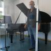 Der Gemündener Musikschulleiter Mathias Weis hinter der  Plexiglastrennwand für den Unterricht mit Blasinstrumenten.