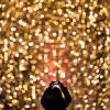 Eine Frau fotografiert in Hamburg die Fassade eines mit Lichterketten weihnachtlich geschmückten Einkaufszentrums. Weihnachtliche Postings haben rund um das Fest Hochkonjunktur in den Sozialen Medien.