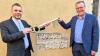 Pfarrer Christian Nowak übergibt Bürgermeister Jürgen Götz symbolisch Schlüssel für das Haus der Begegnung.
