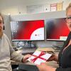Tanja Bartsch, Leiterin Notrufzentrale Unterfranken und Beratungszentrum Bayern, gratuliert Tobias Engelhardt mit einem Gutschein zum Dienstjubiläum.