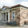 Die Aussegnungshalle auf dem Gerolzhöfer Friedhof wird saniert. Vor allem geht es um einen Umbau der Innenräume. Auf der Südseite (rechts im Bild) wird zusätzlich zu dem portikusartigen Hauptportal ein zweiter, barrierefreier Zugang geschaffen.