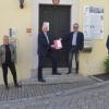 Gabriele Ott-Richebächer und Simone Ender, die ehrenamtlichen Geschäftsführer des Dorfladens, der scheidende Landrat Eberhard Nuß, der scheidende Bürgermeister Andreas Hoßmann, der neue Bürgermeister Christian Holzinger und Gemeinderat Bernd Meyer (von links) bei der Übergabe der Baugenehmigung.