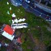 Eine Drohne dokumentiert das furchtbare Busunglück auf Madeira. Der weiße Ausflugsbus, der die Böschung hinunterstürzt und sich mehrfach überschlägt, wird von einem kleinen Haus gestoppt und bleibt auf der Seite liegen.