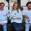 Sänger und Musiker Sebastian "Sebbo" Geng (rechts), Mediendesignerin Nadja Wohlfart sowie Bürgermeister Marcus Wessels präsentieren das CD-Cover sowie die Plakate für die Premiere des Songs "Wir sind Wittighausen!" am kommenden Samstagabend auf dem Wittighäuser Weindorf und der Vorstellung des Musikvideos bei einer Gala am 22. August um 19 Uhr im Kindergartensaal in Unterwittighausen.