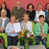 Sie mögen sie alle: Anni Schmitt mit Blumen und Schärpe im Kreis der Mitarbeiter im Familienunternehmen Czerny.