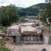 (ong)    Baukräne und Gerüste prägen das Bild im Sinngrund bei Rieneck. Durch den Bau der Ortsumgehung wird die Staatsstraße 2303 aus der Ortslage genommen und in den Talgrund der Sinn verlegt. Auf Höhe des Rienecker Friedhofes im Bildhintergrund beginnt aus Richtung Burgsinn die neue Umgehungsstraße und quert die Sinn und den Sinngrund mit dem Brückenbauwerk „Sinnbrücke Nord“ (hinten). Das Brückenbauwerk 2, mit einer vorgesehenen Geh- und Radwegunterführung, ist ebenfalls nahezu fertiggestellt. Danach wird mit einem geplanten Kreisverkehr die Umgehung an die „Schellhofstraße“ und den Rotenberg und somit an das Neubaugebiet „Schellhof“ und den Altort angebunden. Unmittelbar danach wird die Sinn ein zweites Mal mit der gerade im Bau befindlichen „Sinnbrücke Süd“ gequert. Im Vordergrund ist zuerkennen, wie ein Teilelement geschalt und die Betonierung vorbereitet wird. Dazu die Baubeschreibung des Straßenbauamtes: „Das Bauwerk selbst ist als achtfeldriger Durchlaufträger mit einer Gesamtstützweite von 218,5 Meter – Einzelstützweiten zwischen 23,5 und 29 Meter – und einem einstegigen Spannbeton-Plattenbalkenquerschnitt konzipiert. Der Überbau wird hierbei in Ortbetonbauweise auf einem Traggerüst hergestellt.“