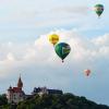 Farbenfrohe Luftfahrzeuge: vier Heißluftballone beim Anflug auf die Heldburg in Südthüringen.