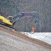 Sanierung des Monte Scherbelino: Ein Bagger bedeckt die ehemalige Deponie mit Sand, darauf kommt dann die Abdeckfolie.