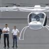 (lsw)   Spektakulärer Flugtest in der Karlsruher Messe-Halle: Der neuartige Volocopter, eine Art Hubschrauber mit Elektroantrieb, hat am vergangenen Wochenende seinen Jungfernflug erfolgreich geschafft. Am Mittwoch demonstrierten die Entwickler des Karlsruher Elektro-Senkrechtstarters für einige Minuten die Flugtauglichkeit des Zweisitzers in der 22 Meter hohen Halle vor Journalisten. Allerdings unbemannt – der Prototyp hat noch keine Zulassung. Anstelle eines Menschen flog in dem ferngesteuerten Volocopter ein Schrauben-Sack mit vergleichbarem Gewicht mit. Gesteuert wurde der schneeweiße Elektroflieger ohnehin von außen per Joy-Stick. Manche sehen mit der mehrfach ausgezeichneten Entwicklung der Firma e-volo eine neue Ära angebrochen. Aus Sicht der Erfinder könnte der Volocopter das künftige Flugtaxi in Großstädten werden. Im Kleinformat werden solche Gefährte schon als Drohnen verwendet, die im Feindesland spionieren können. Auch Firmen und Fotografen nutzen sie zur Geländeüberwachung und für Luftbilder. Der Volocopter wird von 18 elektrisch betriebenen Rotoren angetrieben. Er ist nicht nur umweltfreundlicher und leiser als ein herkömmlicher Hubschrauber – er ist wegen seiner ganz anderen Technik nach Überzeugung seiner Entwickler auch sicherer: Sollten Propeller ausfallen, soll die Kraft der übrigen für den Weiterflug reichen, erläuterte einer der Volocopter-Erfinder Stephan Wolf. Mit dem ersten bemannten Flug rechnet er im kommenden Frühjahr.Drei Männer hatten vor drei Jahren die Idee für die „Innovation made in Karlsruhe“, wie Wirtschaftsbürgermeisterin Margret Mergen beim Demo-Flug stolz vermerkte.