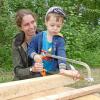 „Wer will fleißige Handwerker seh‘n, der muss in den „Waldkindergarten geh‘n…“: Der dreijährige Julian mit Kindergartenleiterin Lea Schäfer beim Sägen eines Holzstücks für die neue Sitzbank. Diese steht künftig allen Wanderern und Spaziergängern zum Verweilen zur Verfügung.