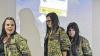 Themengerecht: Die Realschülerinnen Jelana Hohmann, Anne Hohmann und Melissa Jäger im Bundeswehr-Outfit vor dem Bild des Truppenübungsplatzes Wildflecken.