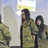 Themengerecht: Die Realschülerinnen Jelana Hohmann, Anne Hohmann und Melissa Jäger im Bundeswehr-Outfit vor dem Bild des Truppenübungsplatzes Wildflecken.