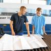 Metallbauer Matthias Eck zeigt dem Auszubildenden zum Tischler Jonas Haaf den Umgang mit der Laser-Schneidmaschine.