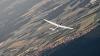 (ret)   Zum Saisonstart bietet der Aero Club Tauberbischofsheim für Nichtmitglieder die Gelegenheit, einen Einblick in den Segelflugsport zu nehmen. Hierzu wird am Wochenende vom 16. und 17. April die Möglichkeit geboten, das Segelfliegen auf dem Platz des Flugschülers kennenzulernen. Alle zum Segelfliegen notwendigen Dinge – einschließlich der Steuerung – dürfen selbst durchgeführt werden. Man erlernt wie ein soeben erst beginnender Flugschüler, auch ohne fliegerische Vorkenntnisse das Flugzeug sicher zu führen. So kann jeder selbst prüfen, ob dieses Hobby ihm gefällt. Der Startvorgang selbst geschieht auf dem Segelfluggelände bei Hochhausen mit einer 320 PS starken Seilwinde, welche ein 1000 Meter langes und 4,6 Millimeter dickes Stahlseil einzieht. Das Segelflugzeug steigt dabei in weniger als einer Minute raketenartig auf rund 350 Meter über Grund. Danach gilt es für den Segelflugpiloten, schnell einen Aufwind zu finden und in diesem rasch Höhe zu gewinnen. Dabei profitieren die Segelflieger des Aero Clubs vor allem von den trockenen Hängen des Tauber- und Leintales, welche eine ideale Voraussetzung zur Ausbildung dieser aufsteigenden Thermikblasen darstellen. Ist er hochgestiegen, kann der Flieger die Höhe in Strecke umsetzen und beispielsweise in Richtung des nahen Odenwaldes fliegen, wo es bis hinüber ins Rheintal oftmals hervorragende Aufwinde gibt. Es können so Durchschnittsgeschwindigkeiten im Überlandflug von mehr als 100 Stundenkilometern erreicht werden. Nach der Ausbildungsphase kann man in ein bis zwei Jahren den Segelflugschein in Händen halten. Im ersten Jahr der Ausbildung bietet der Aero Club Anfängern eine Pauschalregelung mit allen enthaltenen Starts und Flügen inklusive Fluglehrer an. Unser Bild: Auf dem Überlandflug trifft man oft andere Segelflugzeuge an den gleichen Stellen unter den Cumuluswolken, da sich hier die Aufwinde konzentrieren. Hier trifft der Schulungsdoppelsitzer der Tauberbischofsheimer Segelflieger auf ein weiteres kreisendes Segelflugzeug vom Typ DG1000 aus Ludwigshafen in einem Aufwind hoch über dem Odenwald bei Mudau.