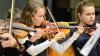 (krit)   Ein Konzert für drei Klaviere und Streichorchester von Johann Sebastian Bach haben Schüler wie Lehrer des Martin-Pollich-Gymnasiums bei der Auftaktveranstaltung zum diesjährigen Schuljubiläum gespielt. Doch das schöne Konzert nur ein einziges Mal aufzuführen, war zu wenig. In einem gemeinsamen Konzert mit den Streichern der Schule war es am Mittwochabend noch einmal zu hören. Für den stellvertretenden Schulleiter Stefan Wintersteiner ging damit ein Traum in Erfüllung. Er spielte eines der drei Klaviere in Bachs Konzert, die beiden anderen wurden von Victoria Rachmetow und Arina Klassen besetzt. So durfte sich das wohlfeile Publikum in der Schulaula über das treffliche Konzert erfreuen, in dem nicht nur die Pianisten, sondern auch die Streicher und Dirigent Urs John überzeugten. Mit dem Begriff „vielsaitig“ war das Konzert in der Aula überschrieben. Viele Saiten brachten die Streicher der Schule unter der Leitung von Magdalene Schmid-Schindler mit. In gemeinsamen Auftritten wie in kleinen Solos, die vor allem von den Streich-Zarten, den jüngsten Sprossen des musischen Zweigs der Schule, gestaltet wurden. Ella Zirk spielte ein Konzert in a-Moll von Oskar Rieding, Lea Schinski gab gemeinsam mit dem Streichorchester einen Ausschnitt aus einem Vivaldi-Konzert. Einen Ausflug in die „vielsaitige“ Welt der Gitarren bot Nina Breunig mit Variationen von Johann Kaspar Mertz. Mit einem Ausschnitt aus dem Konzert in D-Dur spielte Ramona Beck ein weiteres Werk von Rieding, bevor es zu Werken der Komponistin Andrea Holzer Rhomberg ging. Zunächst in einem „Mückentanz“ gespielt von den Streich-Zarten. Ann-Katrin Heitel spielte ein Concertino im russischen Stil und gemeinsam mit den Streich-Zarten die Babuschka-Lieder zum Abschluss. Ein wunderbarer Querschnitt durch die Welt der Saitenklänge von Bach bis in die Gegenwart.