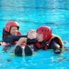 Die angehenden Notfallsanitäter Anne Krönert und David Kraus trainieren im Schwimmbad Rettungstechniken, ihr Kollege Sebastian Sämmer spielt Patient. Foto: Daniel Ostertag / BRK Würzburg