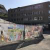 Die „East-Side-Gallery“ des Friedrich-List-Gymnasiums in Gemünden: Die Banner zeigen Kunstwerke von Schülern quer durch alle Jahrgangsstufen, die in den beiden vergangenen Jahren entstanden. Etliche der Zeichnungen und Gemälde wurden bei Wettbewerben preisgekrönt. Andere greifen berühmte Vorbilder von Michelangelo über Jan Vermeer und Caspar David Friedrich bis zu Rene Magritte auf und interpretieren sie neu. Auch Malerei im Stil der australischen Ureinwohner ist zu sehen. Einige Arbeiten stammen auch aus Fotoseminaren. Die Banner mit den Kunstwerken kaschieren die Baugrube vor dem Eingang zur Schule, die vom Abriss der alten Turnhalle der Realschule zeugt und im Lauf der Sanierung des Gymnasiums wieder geschlossen wird. Den Druck der Kunstwerke auf die Banner hat der Schulverein ermöglicht.