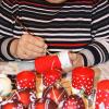Elisabeth Seemann aus Sömmersdorf bemalt rote Kerzen und Weihnachtskugeln mit weißen Schneelandschaften.