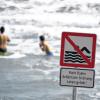 Ein Bild, das Rettungskräfte verärgert: Kinder und Erwachsene baden trotz Verbotsschild an besonders gefährlichen Stellen im Meer.