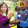 Küken zum Anfassen: Annika und Musamil von der Holzgartenschule in Nürnberg nehmen die kleinen gelben Hühnerbabys vorsichtig in die Hand.