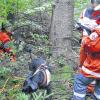 Einsatz im Unterholz: Riesenschnauzer „Fanny“ hat die vermisste Person gefunden. Hundeführerin Beate Crass (Würzburg, links) kümmert sich unter den Augen der Prüfer um die Person und leitet die nächsten Schritte ein.