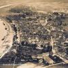 (deu)   Auch diese alte Ansicht von Marktheidenfeld hat Wolfram Blasch aus Erlenbach dem Historischen Verein Marktheidenfeld und Umgebung überlassen. Das Foto dürfte Anfang der 1930er Jahre entstanden sein. Am linken Bildrand auf halber Höhe erkennt man im Main die „Badeanstalt“ als gern in Anspruch genommene Sommerfrische. Am begradigten Marktheidenfelder Mainufer liegen drei Lastkähne. Überhaupt ist der Main ein inzwischen begradigter Fluss, was der Blick Richtung Hafenlohr belegt. Dabei wurden am westlichen Ufer nördlich und südlich der Brücke Buhnen angelegt. Zwischen dem Landpfeiler der Mainbrücke auf der Marktheidenfelder Seite und dem Fluss schlängelt sich noch der Treidelpfad, auf dem die Pferde der Leinreiter die Schiffe flussaufwärts gezogen haben. Dass die Untertorstraße und die Lengfurter Straße früher zu den wichtigsten Straßen von Marktheidenfeld gehört haben, erkennt man an ihrer Breite. Die Rothenbücher Wiese, auf der sich jetzt der Mehrgenerationen-Spielplatz befindet, war seinerzeit mit Büschen und Bäumen bestanden. Zum Main hin grenzt die frühere Plattenschleiferei mit hohem Kamin und Lagerplatz die Rothenbücher Wiese ab. Heute hat dort der Männerchor sein Sängerheim. Am unteren Bildrand sieht man in der Mitte die Bau- und Möbelschreinerei Grön mit ihrem großen Lager- und Bauplatz. Die Turnhalle auf dem angrenzenden Areal war noch nicht errichtet. In der Mitteltorstraße ragt zurückgesetzt der Kamin der Bürgerbräu in die Höhe, daran grenzt ortsauswärts das frühere Bezirksamt an. Schräg rechts dahinter sieht man die Gebäude der Brauerei/Mälzerei Sorg. Erwähnt sei noch, dass es zwar entlang der Langen Gasse/Luitpoldstraße und jenseits bereits vereinzelte Bebauung gibt, das Karree, das heute in etwa von der (unteren) Petzoltstraße, der Luitpoldstraße, der Bronnbacher Straße und der Straße An der Stadtmauer eingeschlossen wird, war aber nahezu unbebaut und ist kleingärtnerisch genutzt worden.