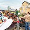 Das große Aufräumen: Helfer schaufeln in der Gemeinde Affing vor beschädigten Wohnhäusern Schutt in einen Container.