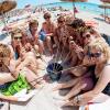 Frauen trinken aus einem Eimer am Strand von Arenal auf Mallorca.