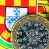 Euromünze auf einer portugiesischen Flagge. Spanien und Portugal sollen vorerst von Geldbußen verschont bleiben.Jens Büttner, dpa