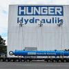 (wde)   Ein in der Firma Hunger Hydraulik hergestellter Großzylinder verließ am Montag das Werk an der Rodenbacher Straße. Mit einem überlangen Sattelschlepper wurde der – im eingefahrenen Zustand – 17,2 Meter lange Zylindernach Antwerpen gebracht und dort aufs Schiff verladen. Er hat einen Außendurchmesser von 1,45 Meter und wiegt 120 Tonnen. Zielort ist Tsingtao in China. Dort soll der Hydraulikzylinder, der Lasten bis zu 2000 Tonnen bewegen kann, auf einer schwimmenden Plattform verwendet werden, mit deren Hilfe bis zu 110 Meter lange Stahlbetonpfeiler in den Meeresgrund gerammt werden sollen. Auf hunderten dieser Pfeiler sollen dann Stege betoniert werden, um Schiffsanlegestellen zu schaffen oder Rohrleitungen zu verlegen. Wie Geschäftsführerin Ingrid Hunger auf Anfrage deutlich machte, ist die Lage im Unternehmen weiterhin angespannt. Bis Ende September werde kurzgearbeitet, danach wieder voll. Sie hoffe, so Hunger, dass bis dahin genügend Arbeit vorhanden sein wird. Ein Problem für den Lohrer Hydraulikzylinderhersteller sei, dass Bedarfsländer wie China und Russland derzeit nicht investitionsfreudig seien; das Gleiche gelte für Südkorea. Dennoch versuche sie, in Russland neue Geschäfte anzubahnen und auch mit Teheran wieder ins Geschäft zu kommen, sagte Ingrid Hunger. An einigen Großprojekten sei das Unternehmen fest dran.
