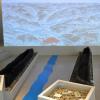 Auf einer Leinwand wird der gesamte Mainlauf gezeigt. Dort „entspringt“ auch der Fluss, der sich sich als blaues Band durch die Ausstellungsräume windet. Flankiert an seiner „Quelle“ von Einbäumen aus dem Mainschotter.