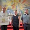In der katholischen Kirche Maria Königin zeigte der evangelische Geistliche Andreas Biesold (links) das Bild „Ökumene“, welches auch das Leitmotiv der Karikaturen-Ausstellung ist. Ilka Seichter, Leiterin des Diözesanbüros Bad Neustadt (Mitte), hatte sich im Vorfeld um die Organisation gekümmert, was auch Kurat Andreas Hutzler (rechts) freute.