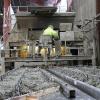 Ein Arbeiter gießt mit seiner fahrbaren Betoniermaschine im Betonwerk Neuendorf die Schalung einer Halbfertigdecke mit Beton aus.