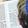 Jüdischer Alltag in Deutschland: Ein Schüler der Joseph-Carlebach-Schule in Hamburg, der eine blaue Kippa trägt, schaut in ein Gebetbuch mit hebräischen Schriftzeichen.