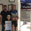 Das Bild zeigt Jubilar Volkmar Döll (rechts) mit Firmenchef Michael Fuchs (links) und dessen Sohn Linus Fuchs, der die Ehrenurkunde freudestrahlend hochhält.