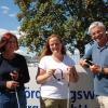 Stockübergabe an die neue Kollegin“. Vor der BFW-Eingangspforte nehmen die beiden BFW-Mobilitätslehrer Andrea Hartwig und Hellmuth Platz Sabine Spies in ihre Mitte. In den Händen halten sie typische Hilfsmittel, Langstock, Knochenkopfhörer und Smartphone. Foto: BFW Würzburg