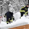 Feuerwehrleute befreien das Dach eines Gebäudes in Ruhpolding von seiner Schneelast. Das THW Haßfurt hat Spezialisten nach Oberbayern geschickt, die bei der Bestimmung von Dachlasten durch Schnee und bei der Entscheidung helfen, ob Dächer von Schnee geräumt werden sollten.
