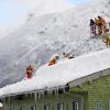 Feuerwehrleute im oberbayerischen Inzell räumen den Schnee vom Dach eines Hauses.