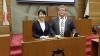 Bürgermeisterin Naomi Koshi und Bürgermeister Adolf Bauer am Rednerpult des Sitzungssaals mit Stadtwappen im Rathaus der Stadt Otsu.