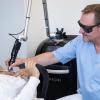 Dr. Tilmann Bohne zeigt an einer seiner Mitarbeiterinnen, wie die Tattooentfernung mit dem Lasergerät funktioniert.