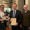Die Geschäftsführer Jürgen Johanni (rechts) und Philipp Zobel (links) überreichten Helmuth Hufnagel neben einer Urkunde  einen Präsentkorb.