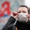 Eine Frau trägt vor einer Apotheke eine Mund- und Nasenmaske. Der erste Fall des Corona-Virus in Deutschland hat die Nachfrage nach Atemmasken in Apotheken stark erhöht. Ein Infektionsexperte hält dagegen Schutzmaßnahmen von Bürgern, wie das Tragen von Mundschutz, derzeit für unnötig.