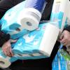 Ein Mann trägt eingekauftes Toilettenpapier und Küchenrollen aus einem Supermarkt. Neben Lebensmittel hamstern viele Verbraucher in der Corona-Krise vor allem Klopapier.