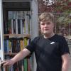Jona Gerhard vor seinem selbstgebauten offenen Bücherschrank, der derzeit noch frei zugänglich auf dem Grundstück seiner Eltern steht und trotzdem schon rege genutzt wird